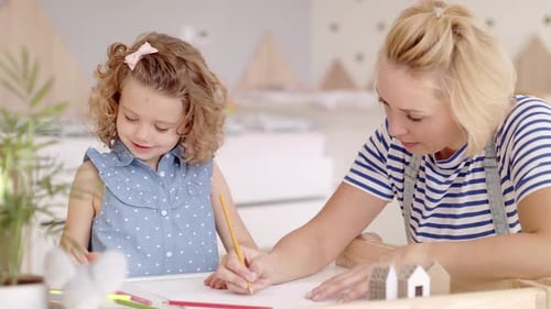 Mother and daughter drawing together indoors at table