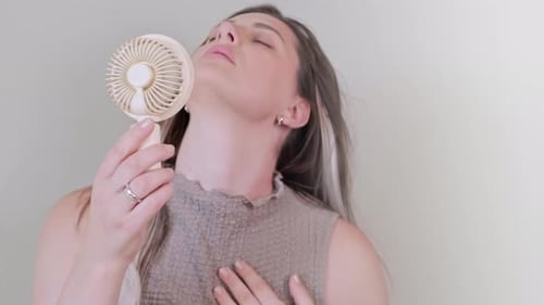 Woman Cooling Herself with Small Personal Fan