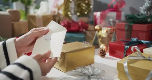 Close up of girl hands unpacking present gift box winter christmas decorations on red background.