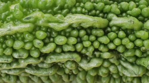 Une gourde amère, un légume souvent utilisé comme ingrédient en cuisine, est posée sur une table en bois.