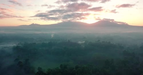 aerial view at sunrise over the mountains surrounding the majestic borobudur temple in indonesia