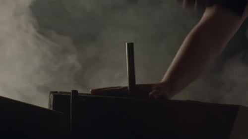 Hands Hammering Metal Rod in Dim Lighting