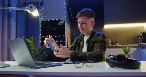 Young Man Playing Game on Smartphone at Night