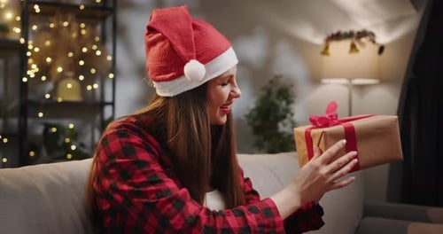 Woman Holding Wrapped Christmas Present Indoors at Night