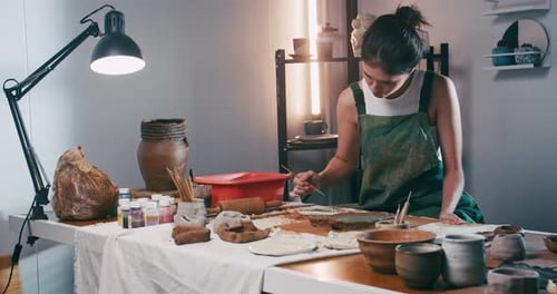 A female ceramicist is creating a new pottery in the workshop. Asian woman is enjoying pottery work.