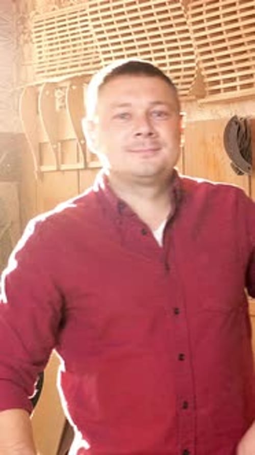 Skilled Craftsman in a Workshop Wearing a Red Shirt Surrounded By Woodworking Tools and Materials
