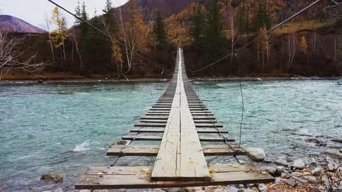 A Stunning Suspension Bridge Gracefully Arches Over the Turquoise River Set in an Enchanting Autumn