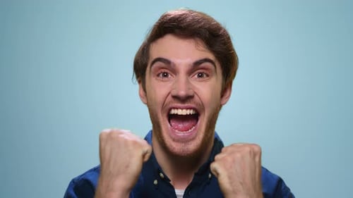Excited man celebrates success with yes gesture in studio slow motion portrait