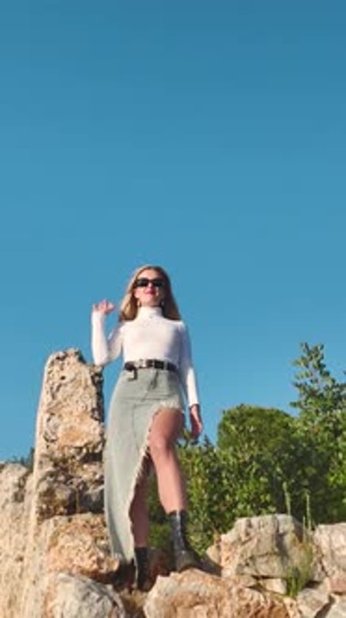 A Scenic Blend of Elegance and Nature As the Model Poses on a High Cliff