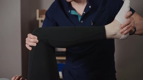 A Male Osteopath Performs Physical Therapy on a Female Patient The Doctor Looks at the Condition of