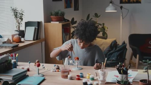 Young Person Painting Solar System Model at Desk