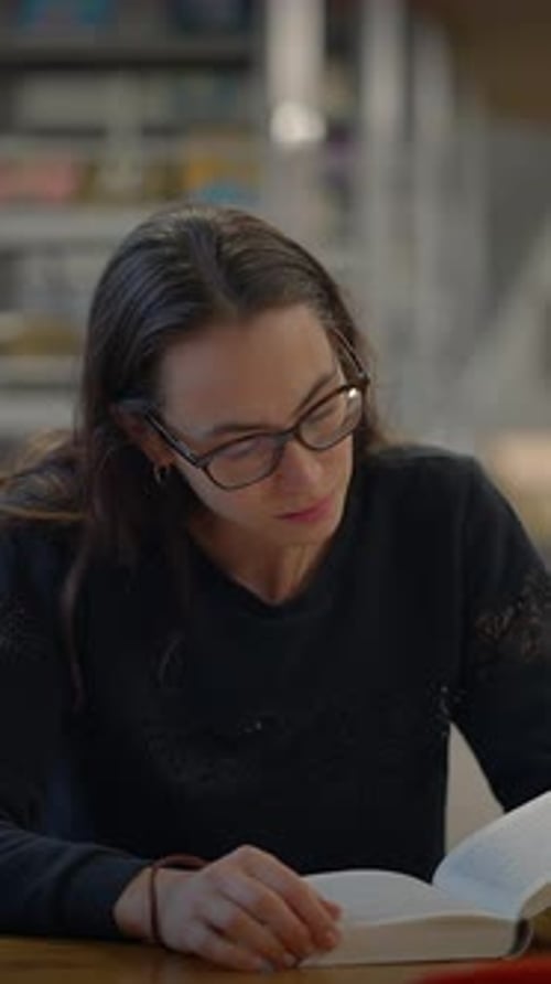 A Woman Reading a Book in a Contemporary Library Environment Filled with Resources and Ideas