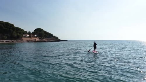 Man Paddle Boarding in the Calm Ocean Near the Coast