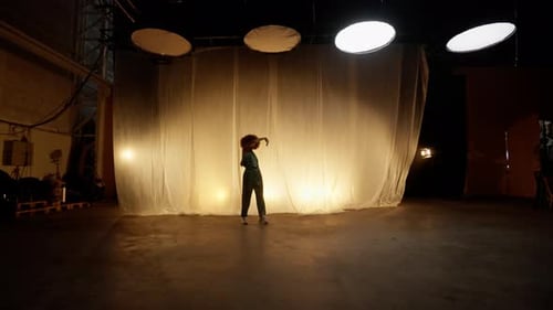 Professional Dancer Performing Against Stage Curtain with Warm Backlit