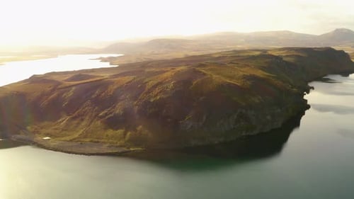AERIAL : Wide view of a mountain lake, rocky mountain surrounded by clean water.