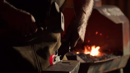 Blacksmith Forging Red-Hot Metal in Dark Workshop