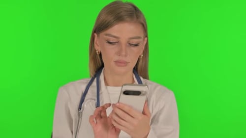 Portrait of Female Doctor Browsing phone on Green Background