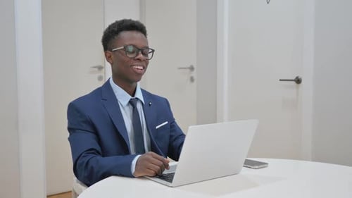 Smiling Young Adult in Suit Uses Laptop for Video Call