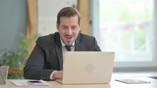 Excited Businessman Working on Laptop in Office