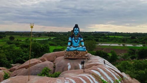 statue de Lord Shiva au sommet d'une pierre de granit en arrière-plan, champs cultivés, terres, refoulement, Drone