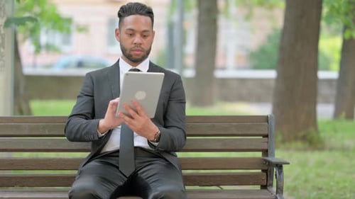 Businessman Using Digital Tablet while Sitting Outdoor on Bench