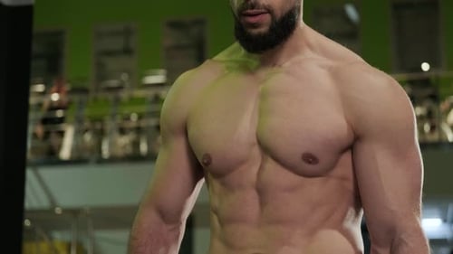 A Handsome Muscular Man with a Beard Poses in the Gym