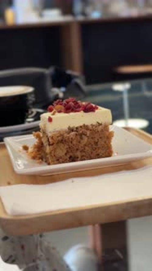 Ein Schuss vom Kuchen des Influencers. Ein Stück Schichtkuchen mit Sahnebelag und roter Beilage wird auf einem Teller serviert
.