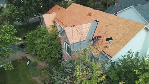 Roofers Installing a New Roof on an Residential Building Wide Shot