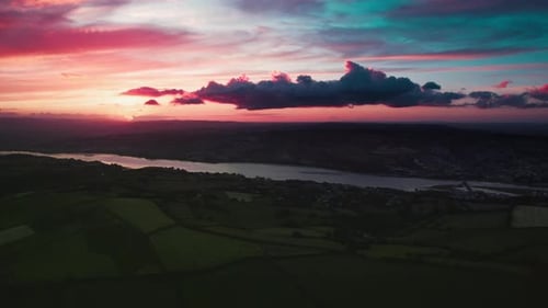 Breathtaking Pink Dawn or Dusk Over Lush Green Fields By a River Captured From Above Aerial View