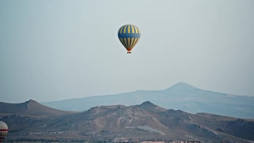 Hot Air Balloon Floats Over Mountainous Landscape