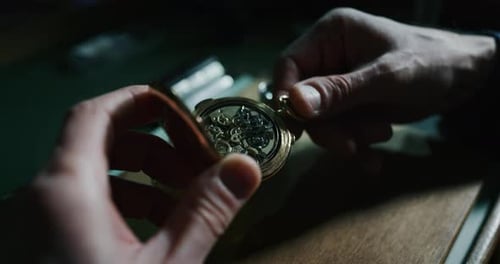 Slow motion close up of a professional watchmaker repairer working on an old vintage pocket watch