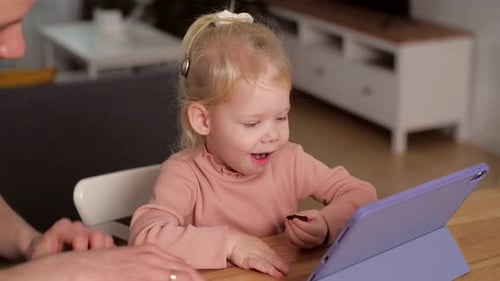 A Child with Cochlear Implants Plays with a Tablet Computer with His Father