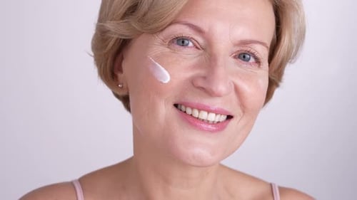 Woman Applies Cream to Her Smiling Face
