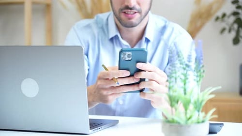 Adult using Smartphone at White Desk with Laptop