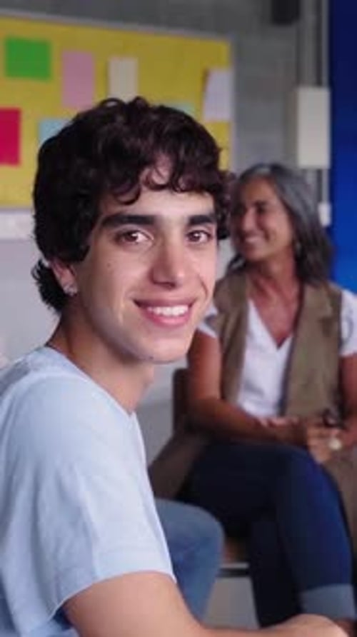 Portrait of Young Man Sitting in Circle Next to His Schoolmates at Class Looking at Camera Smiling