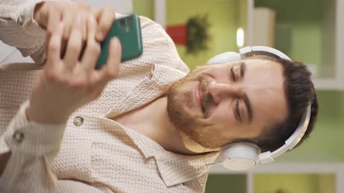 Man Listens To Music on Phone with Headphones