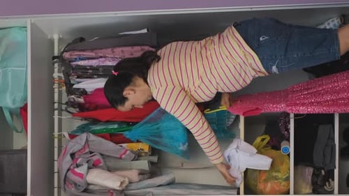 Woman Organizes Clothes in a Closet at Home