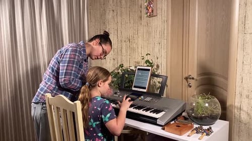 Child Learning Piano with Adult Guidance