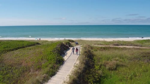 Couple Walking Along Sand Towards Beach & Ocean, Aerial Drone Aerial