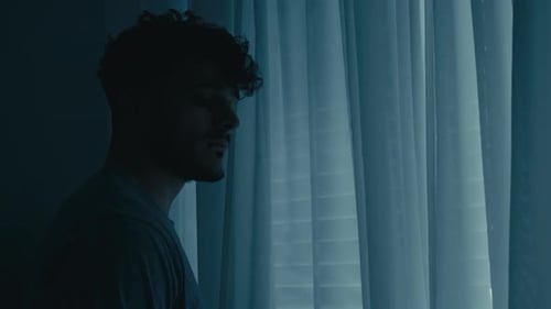 Man Standing Near Window with Curtains and Blinds