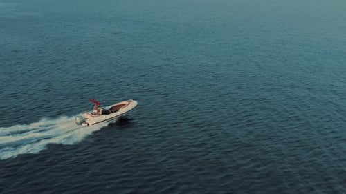 Drone shot of a woman driving speed boat. She is enjoying her summer holiday — beautiful nature.