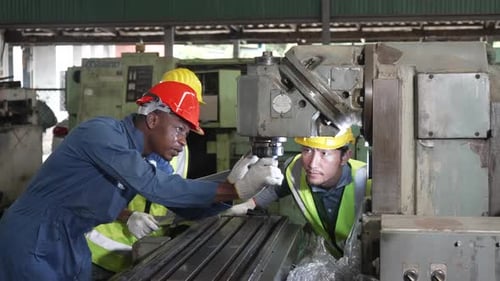 Blue collar workers work at metal factory.