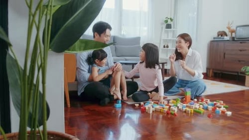 Asiatische Familie mit spielenden Kindern und Bauturm aus buntem Holzspielzeug