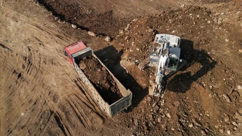Excavator Fills Dump Truck at Construction Site