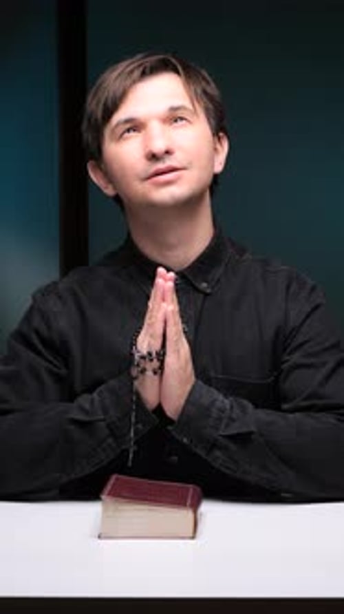 Man Praying with Rosary and Book Indoors