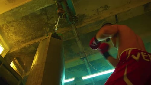 Boxer practicing with a punching bag in dimly lit gym