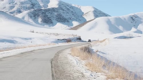 Conduire sur une route de montagne en hiver sur fond de sommets enneigés