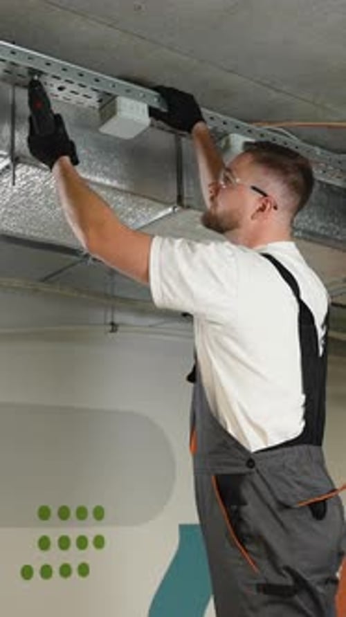 Man Installs Electrical Wiring in Gray Work Overalls