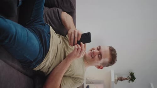 Man Relaxing on Couch Using Smartphone Indoors