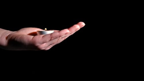 Main de femme avec petite bougie sur fond noir